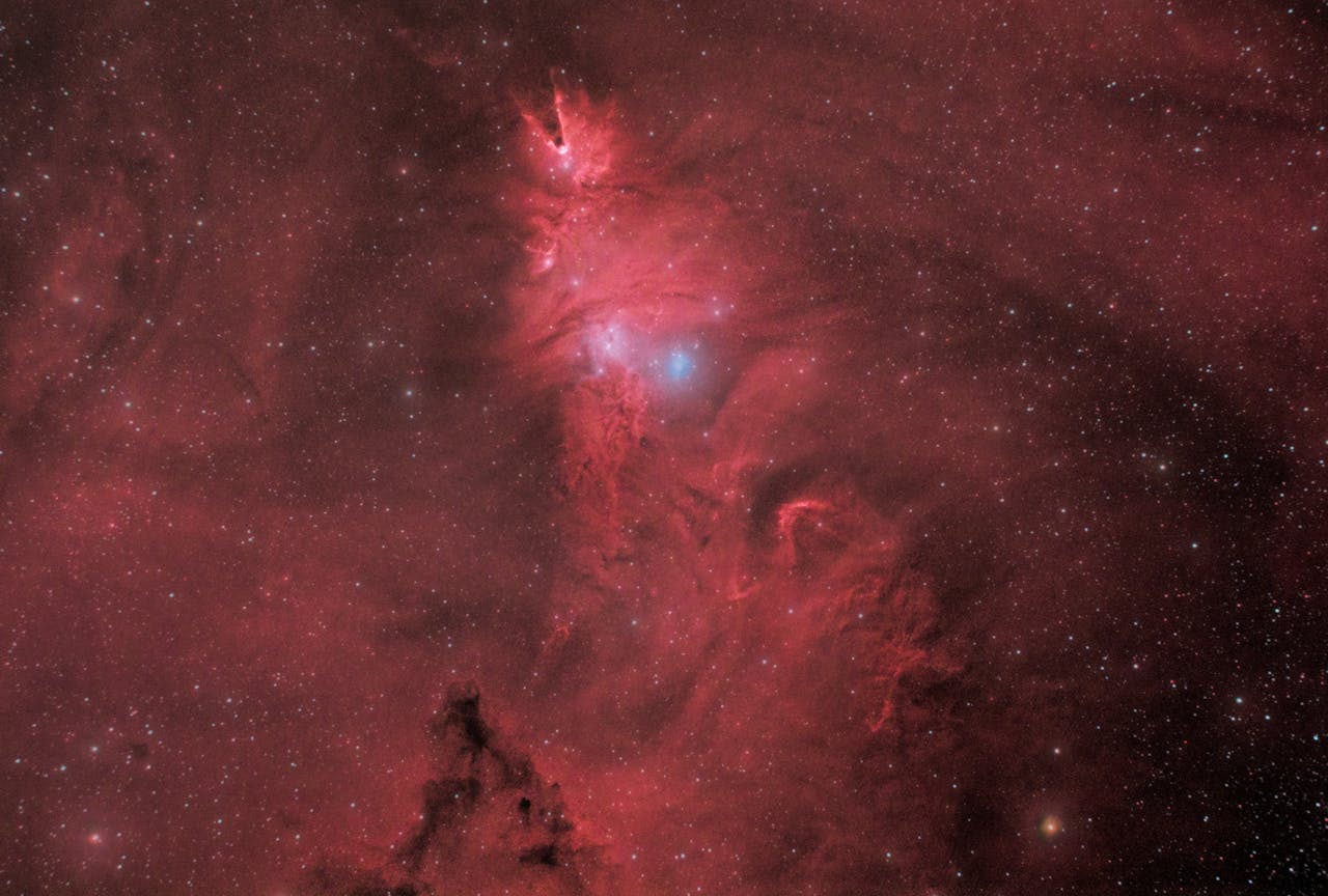 Explore the vibrant colors and intricate shapes of a red nebula amidst a starry sky.