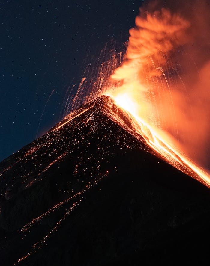 Dramatic eruption of a volcano under a starry night sky, captured in Chimaltenango, Guatemala.