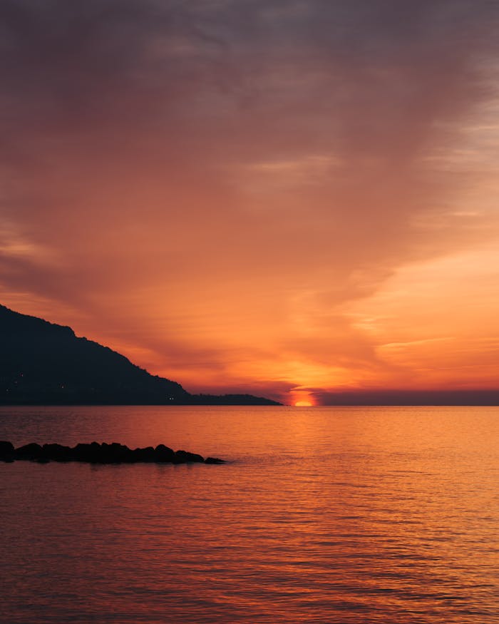 Stunning sunset with vibrant sky hues over a tranquil bay, capturing peaceful evening vibes.